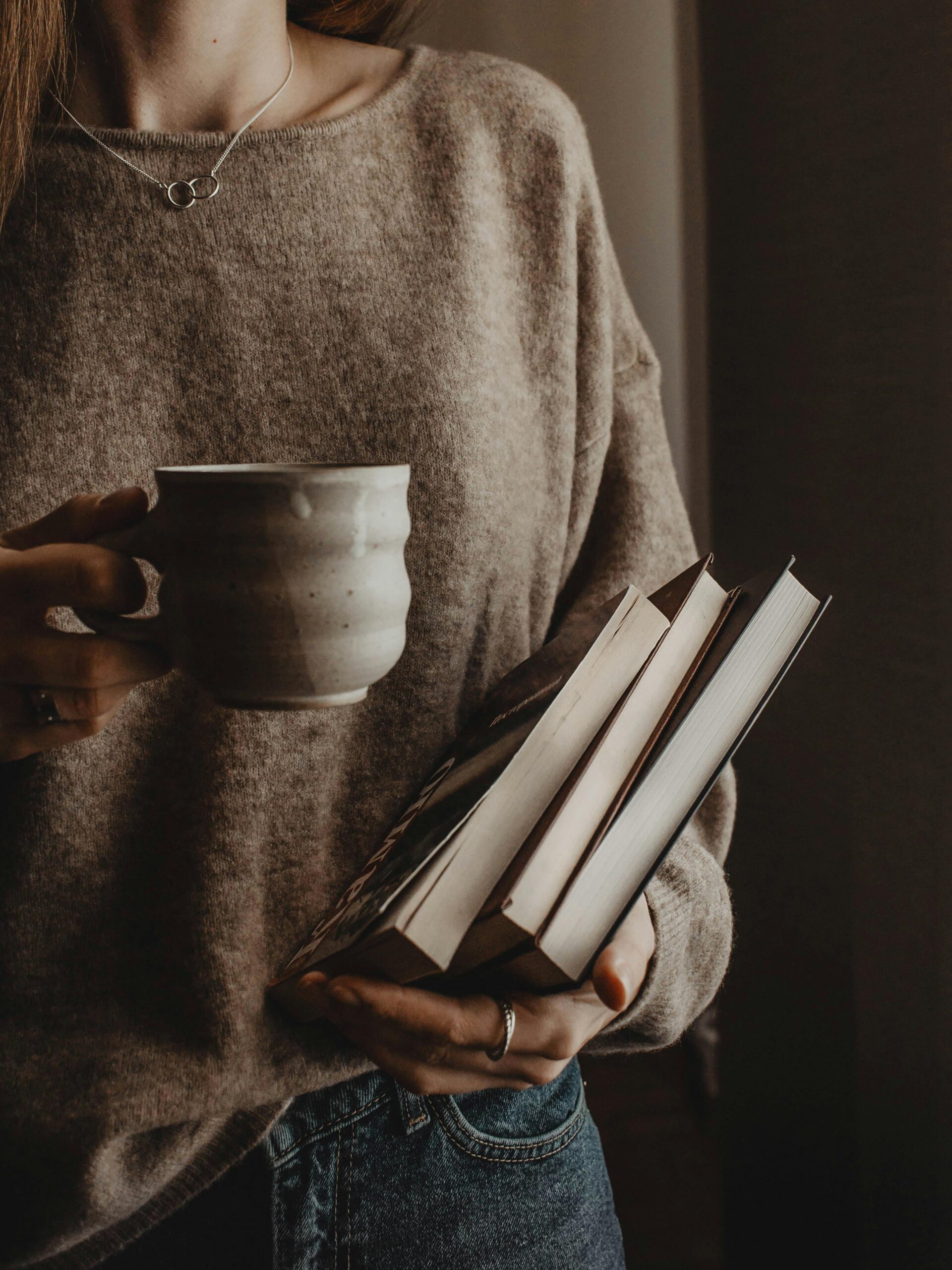 woman holding coffee cup and books